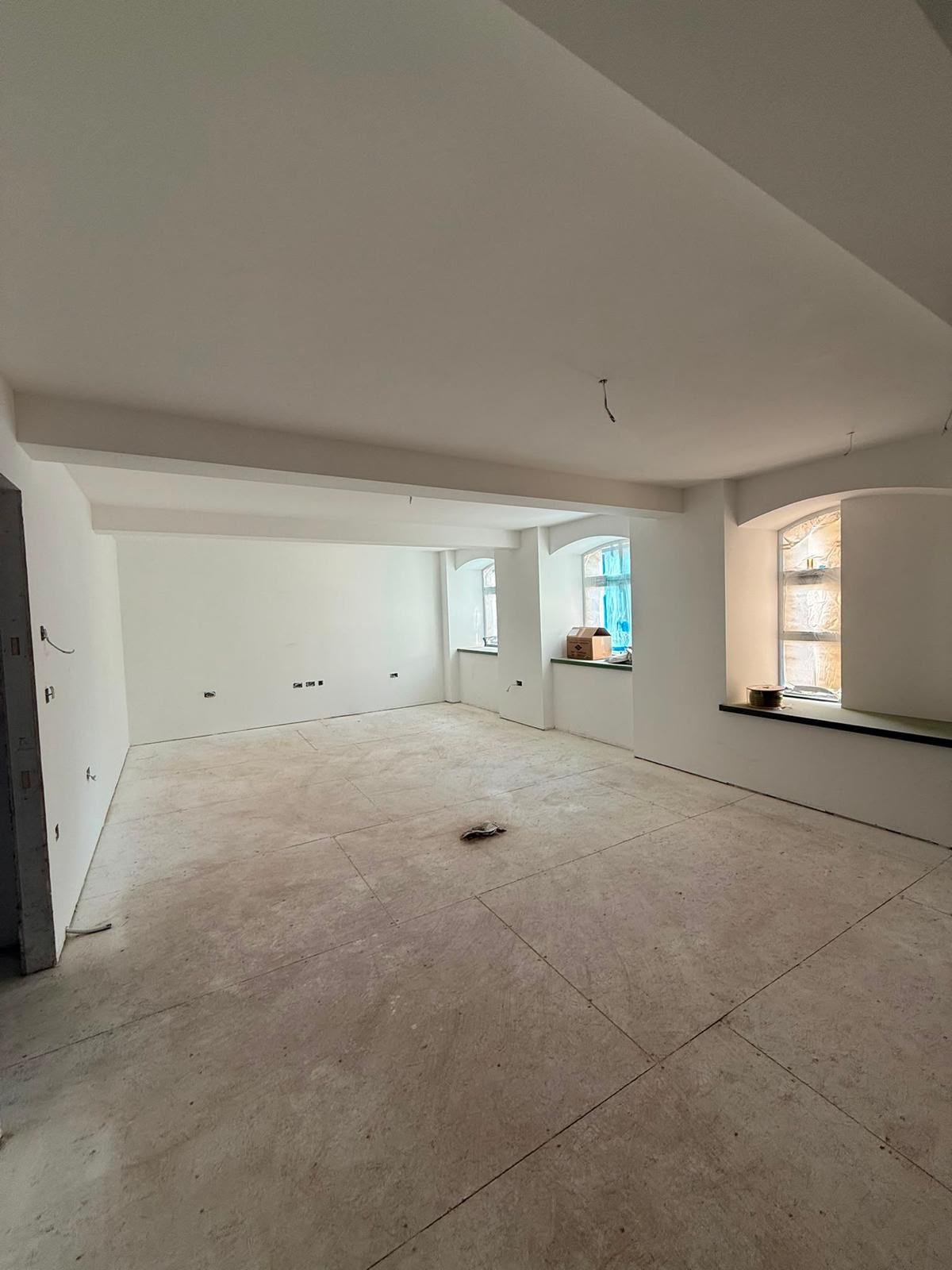 Large open-plan space with freshly plastered walls and arched windows during a commercial refurbishment