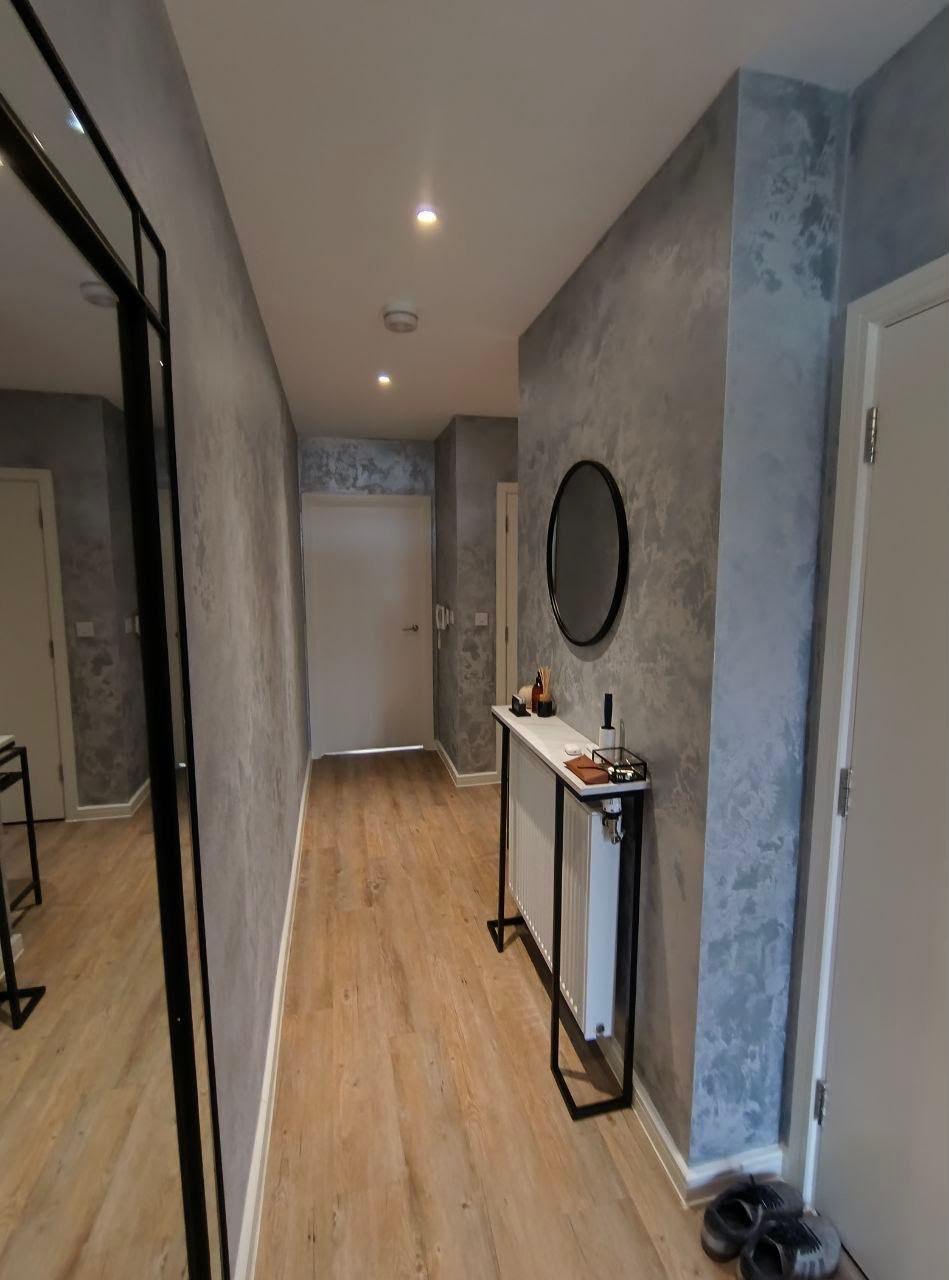 Hallway with a marble-effect feature wall, wood-effect flooring and a black-framed glazed door