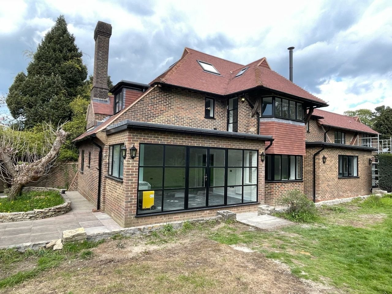 Brick house with a clay tile roof and a single-storey rear section with black-framed glazing