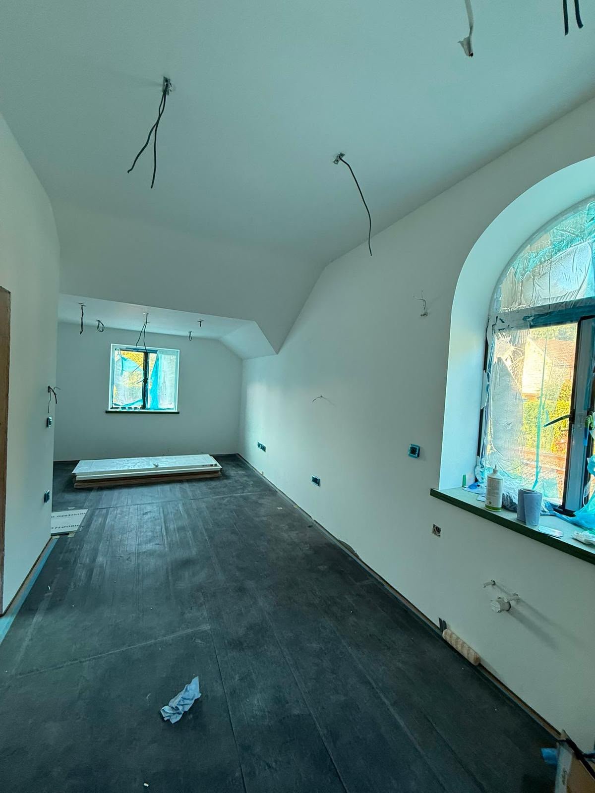 Room under refurbishment with plastered walls, arched windows and protected flooring