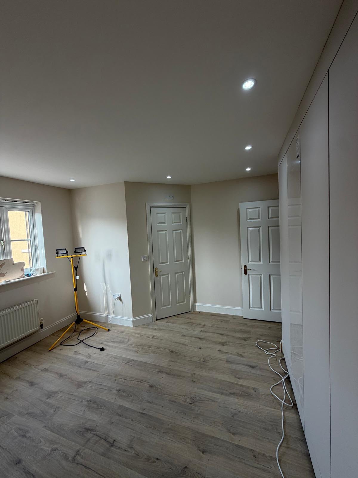 Refurbished room with panelled doors, fitted storage and new wood-effect flooring