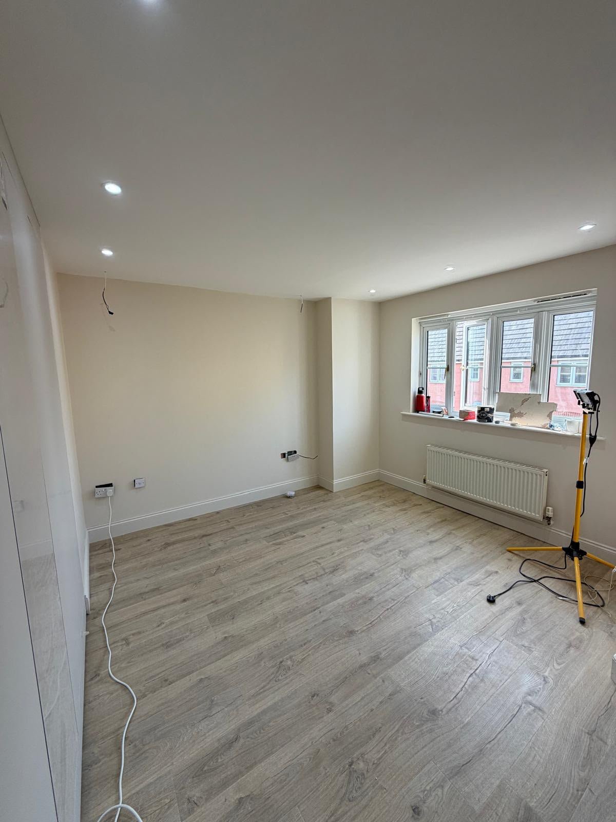 Freshly decorated room with new flooring, radiator and a wide casement window during final finishing