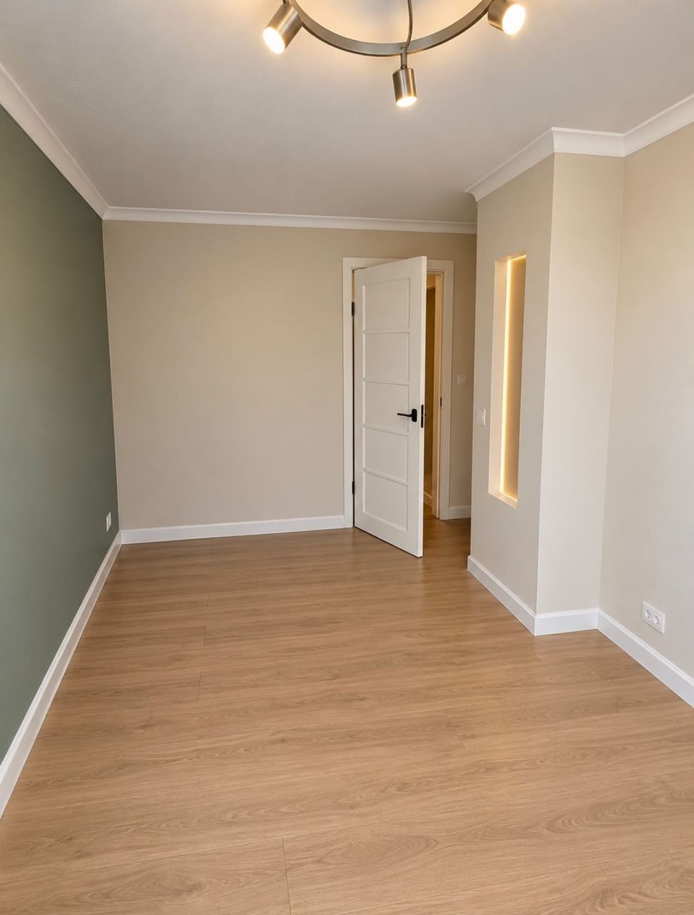 Refurbished room with wood-effect flooring, a sage feature wall, a lit wall niche and a modern ceiling light