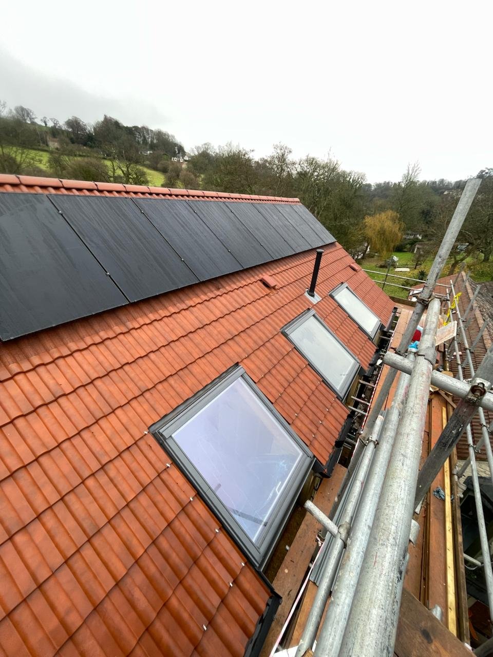 Rooflights and solar panels on a clay tile roof with scaffolding in place