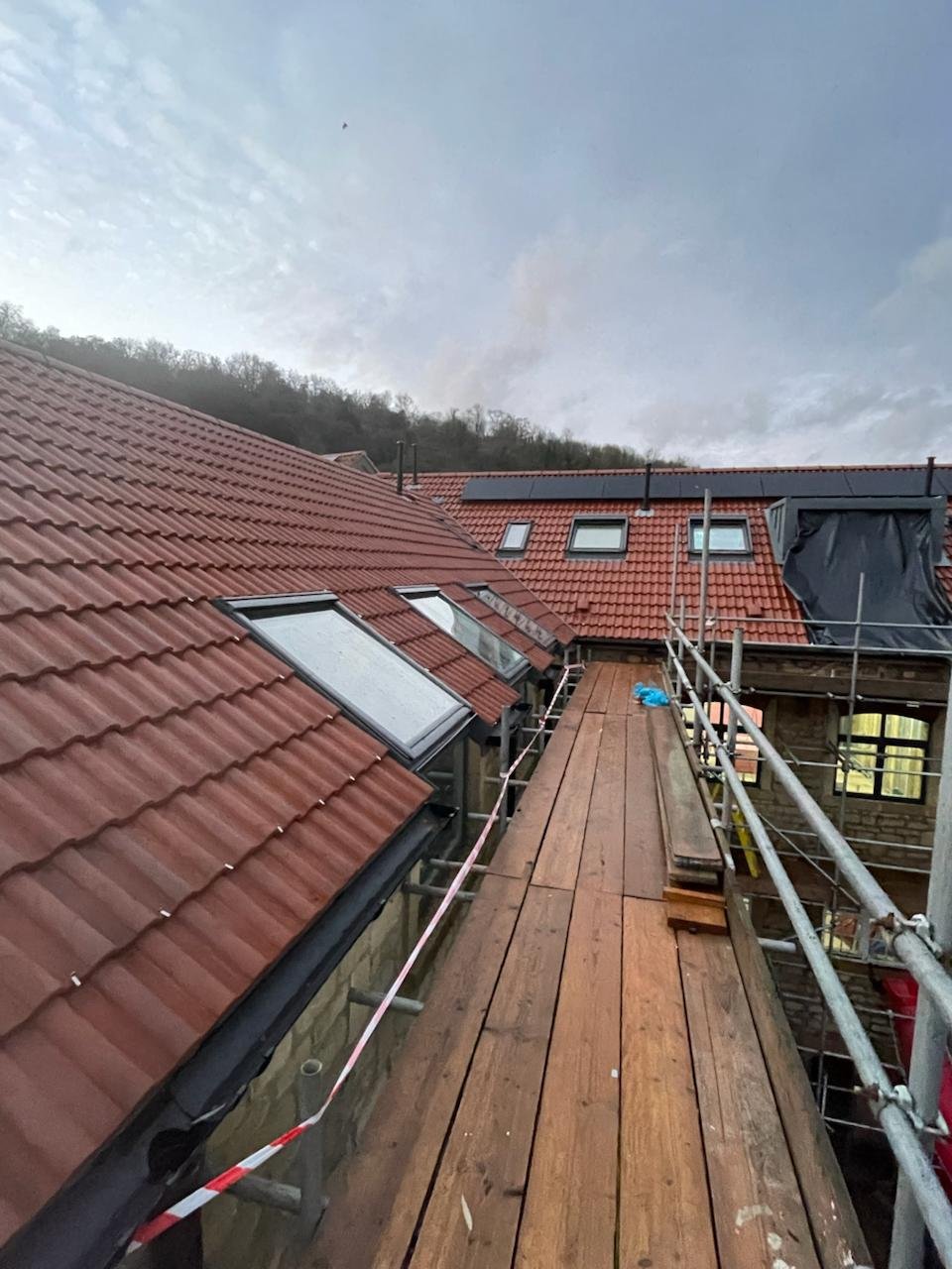 Scaffold walkway along the eaves of a clay tile roof with rooflights