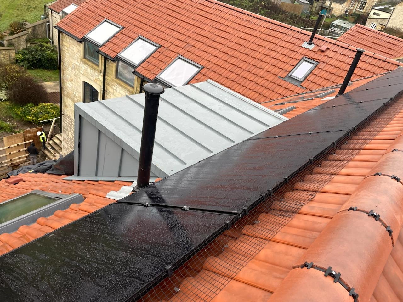 Clay tile roof with integrated solar panels, rooflights and an aluminium-clad dormer