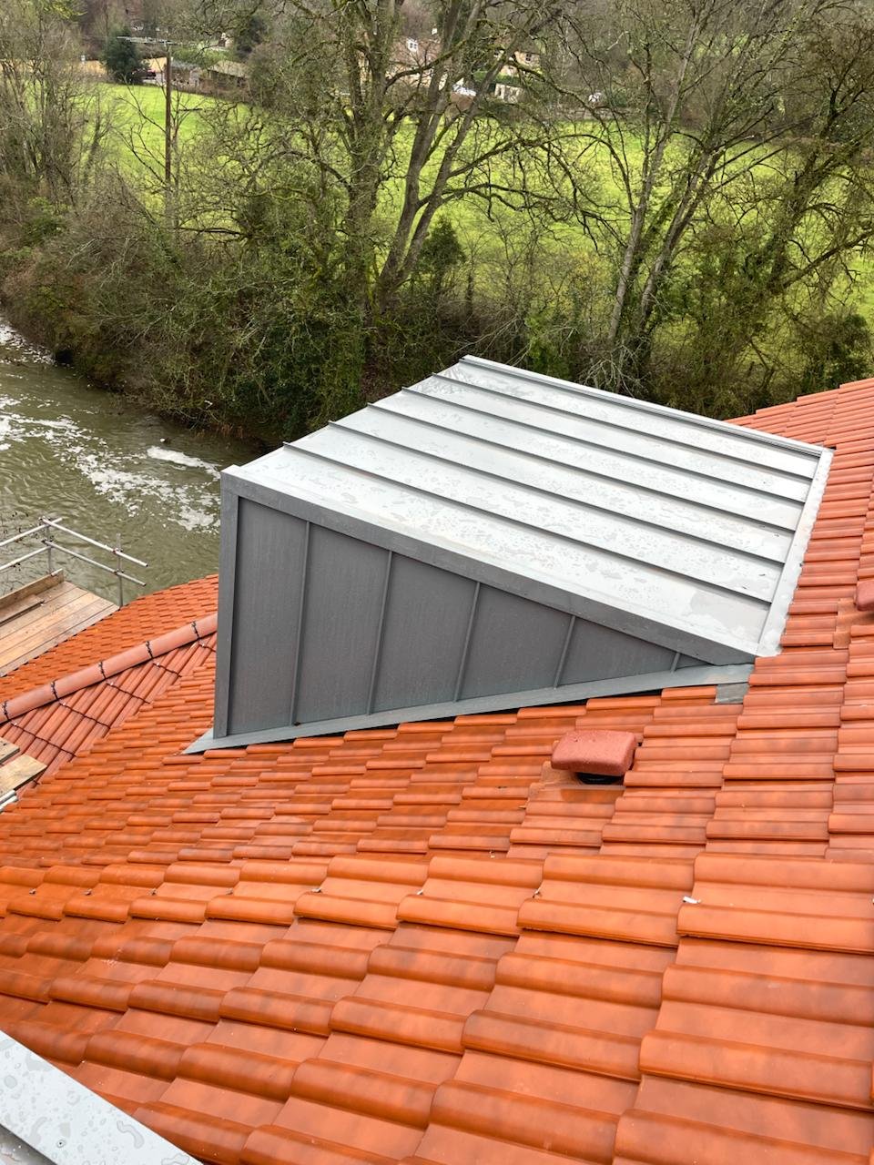 Aluminium-clad dormer set into a new clay tile roof above mature trees